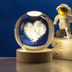 an astronaut figurine next to a snow globe on top of two bookends