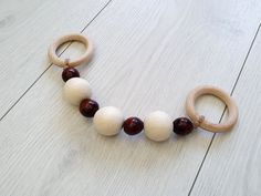 a wooden bead necklace on a white wood floor with red and white beads hanging from it