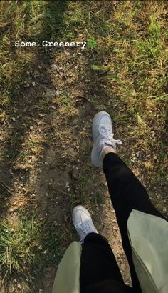 two people standing in the grass with their feet up and one person wearing white sneakers