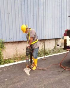 a man in yellow safety gear is using a machine to fix a pipe on the side of a building