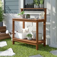 a wooden shelf with potted plants on it in front of a white wall and green grass