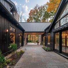 an outdoor walkway leading to two large black buildings with glass doors and windows on each side