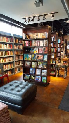 a room filled with lots of books on shelves next to a couch and table in front of it