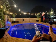 a man sitting in front of a swimming pool holding a bottle