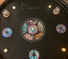 there is a clock with many different colored discs on the face and numbers below it