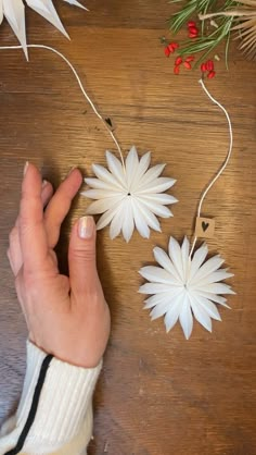 a person's hand reaching for some paper flowers