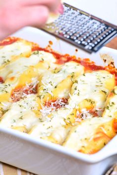 a casserole dish with cheese and sauce in it on a table next to a calculator