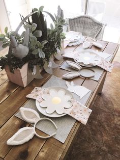 a wooden table topped with white plates and flowers