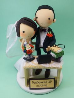 a wedding cake topper with a bride and groom sitting at a desk on it