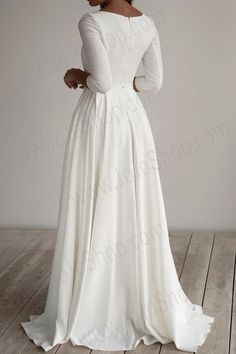 a woman in a white wedding dress standing on a wooden floor with her back to the camera