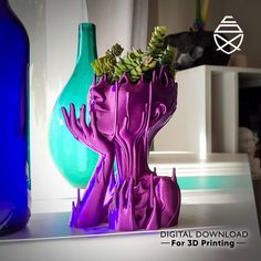 purple and green vases sitting on top of a table next to blue glass bottles