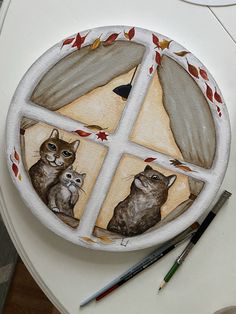 a plate with cats painted on it next to paintbrushes