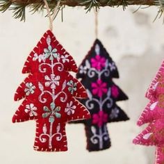 three ornaments hanging from a tree branch with pink and blue decorations on it's sides