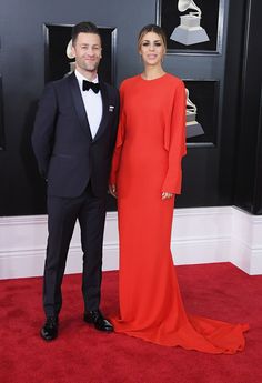 two people standing on a red carpet in formal wear