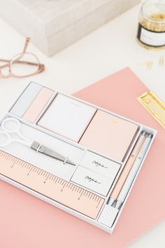 a pink desk with a ruler, pen and eyeglasses