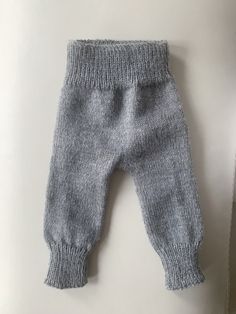 a baby's gray knitted pants laying on top of a white table next to a pair of scissors