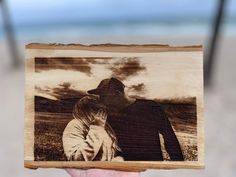 a person holding up a wooden photo with the image of a man and woman on it