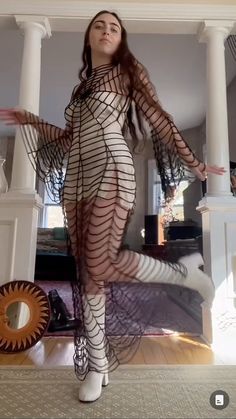 a woman is posing in a fishnet bodystocked dress and heels with her hands out