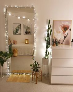 a bedroom decorated in white with lights and plants