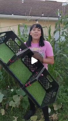 a woman is holding up some grass in front of her house and she has two large baskets