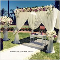 an outdoor wedding setup with white drapes and flowers