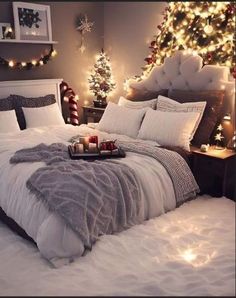 a bed with white comforter and christmas lights on the headboard, in front of a tree