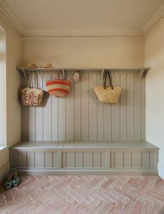 two baskets are hanging on the wall next to a bench in a room with brick flooring