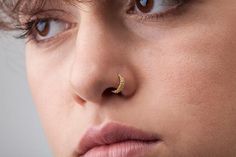 a close up of a person with a nose ring on their nose and one eye open