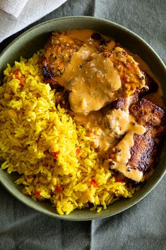 a bowl filled with rice and meat covered in gravy on top of a table