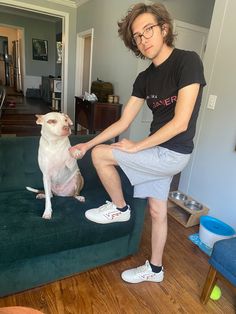 a man sitting on top of a couch petting a dog