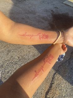 two people holding hands with tattoos on their arms that say, always and forever written in red ink