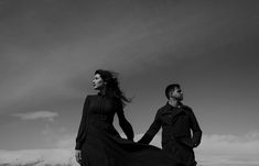 black and white photo of man and woman holding hands with mountains in the back ground