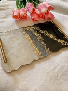 some pink flowers are sitting on a white table cloth and two gold colored trays