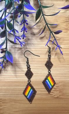 a pair of earrings that are on top of a wooden table next to purple flowers