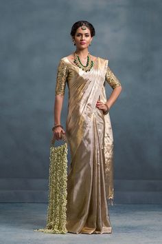 a woman in a gold sari and green necklace standing with her hands on her hips