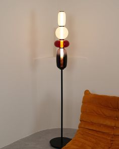 a floor lamp sitting on top of a table next to a brown chair and pillow