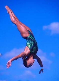 a man doing a handstand in the air on a surfboard under a blue sky