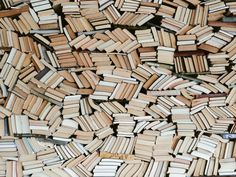 a pile of books sitting next to each other on top of a wooden floor covered in wood planks