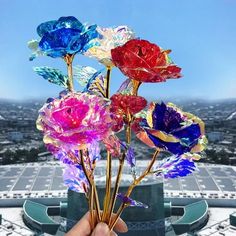 colorful glass flowers are being held up in front of a large building with a view of the city