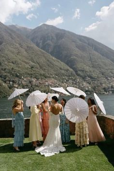 a group of women standing on top of a lush green field next to a lake