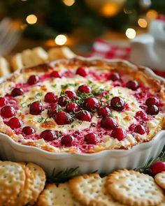 a dish with cheese and cranberries in it on a platter surrounded by crackers