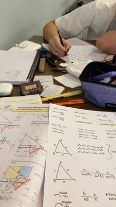 two people sitting at a table with papers and pencils on top of each other