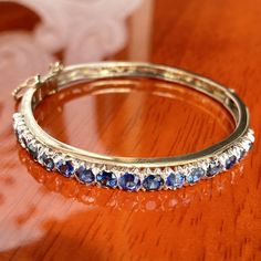 "Timeless elegance and beauty encapsulates this Edwardian style bangle. Set with 17 ocean blue natural no heat sapphires with VS clarity and weighing a mammoth total of 7.00 carats. All being securely set in an open cut white gold collet style, indicative of the period.  It's beauty cannot be overstated enough, the stones sparkle and glow in ways that are truly captivating making this piece a one-of-kind article for avid collectors of old worlds.  The open scroll work has a round half back with a width measuring 4.10mm that tapers to 7.10mm on the top and a thickness that tapers from 5.20mm at the top to 3.00mm at the bottom. Set with seventeen slightly graduating shared split claw white gold settings across the top with a hallow base and \"V\" shaped mounts across the top--fitted with a b Fine Sapphire Bangle Jewelry, Luxury Blue Gemstone Bangle, Sapphire Gemstone Bangle Jewelry, Sapphire Bangle Jewelry For Anniversary, Sapphire Bangle For Anniversary, Sapphire Bracelets With Prong Setting For Anniversary, Anniversary Sapphire Bangle Jewelry, Elegant Blue Round Bangle, Blue Fine Jewelry Bangle For Gifts