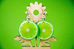 a pair of lime slices are on top of a wooden stand with earrings hanging from it