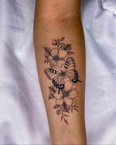 a woman's arm with a butterfly and flowers tattoo design on the left forearm