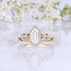 an engagement ring with a large diamond surrounded by small white flowers and greenery in the background