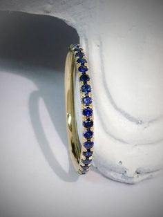 Delicate Royal Blue Sapphire Gemstone Micro Pave Full Eternity Band Ring. Material: 14K Solid Yellow Gold Finishing: High Polished/ Shiny Fit: Comfort Fit/ Rounded Interior Width: 1.6mm Height: 1.6mm Setting: U Micro Pave Set Stone: Natural Blue Sapphire Stone Cut: Diamond Cut, Round Carat Elegant Blue Eternity Band, Blue Eternity Band For Wedding, Classic Blue Stackable Wedding Rings, Blue Sapphire Eternity Band For Wedding, Blue Eternity Band Promise Ring, Blue Round Eternity Band For Wedding, Blue Stackable Eternity Band, Blue Stackable Round Eternity Band, Blue Half Eternity Band Ring