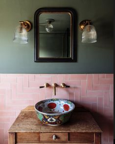 a bathroom sink sitting under a mirror on top of a wooden counter next to a light fixture