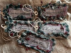 three tags with words on them are sitting on a burlap cloth covered surface