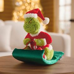 a green stuffed animal sitting on top of a wooden table next to a christmas tree